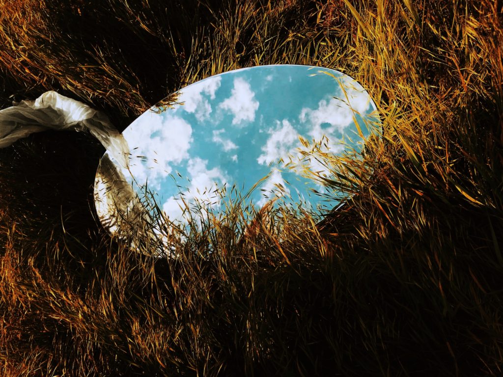 mirror in grass field reflecting clouds
