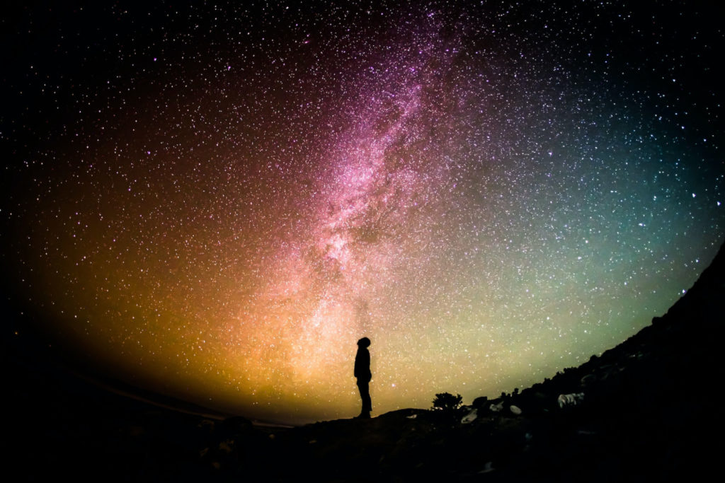 person staring at a colourful starry sky