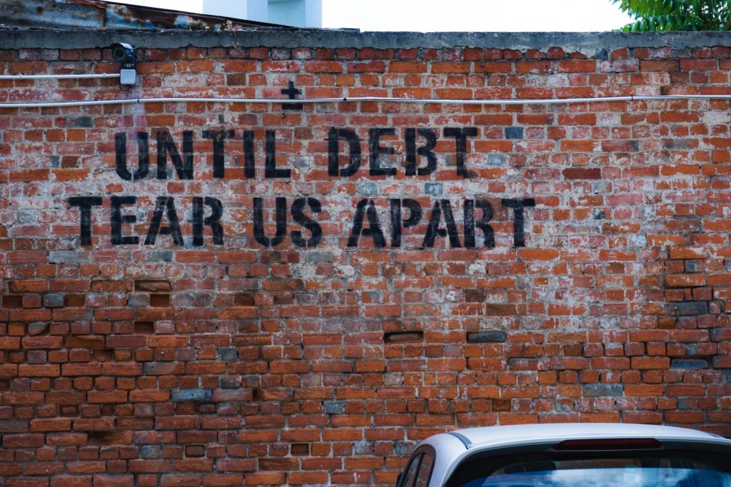 brick wall with the phrase "until debt tear us apart" painted on it