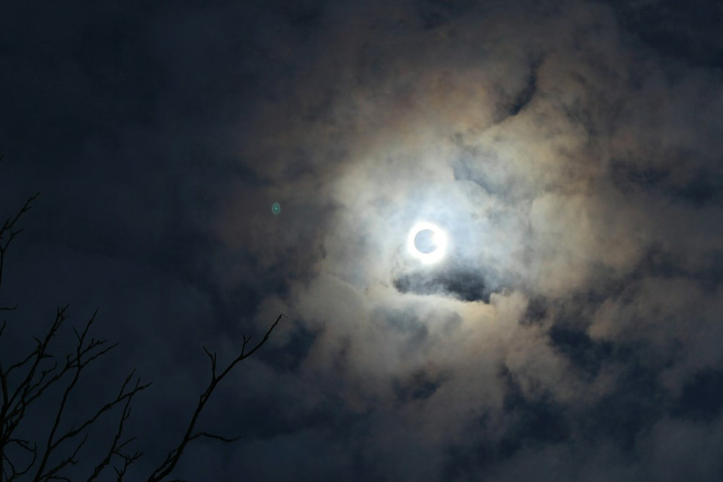 total solar eclipse at its peak surrounded by clouds