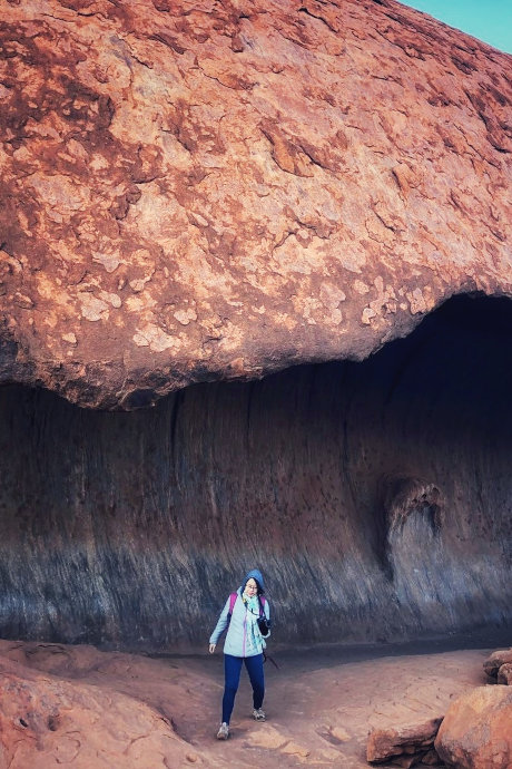 woman holding a camera stepping out of a cave